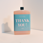 Bottle with a blue label that says 'THANK YOU! LISA' on a light background