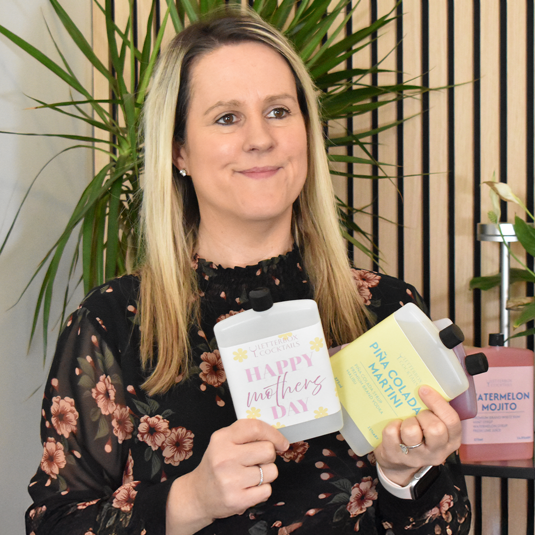 Woman holding two products with letterbox cocktails in a decorative setting