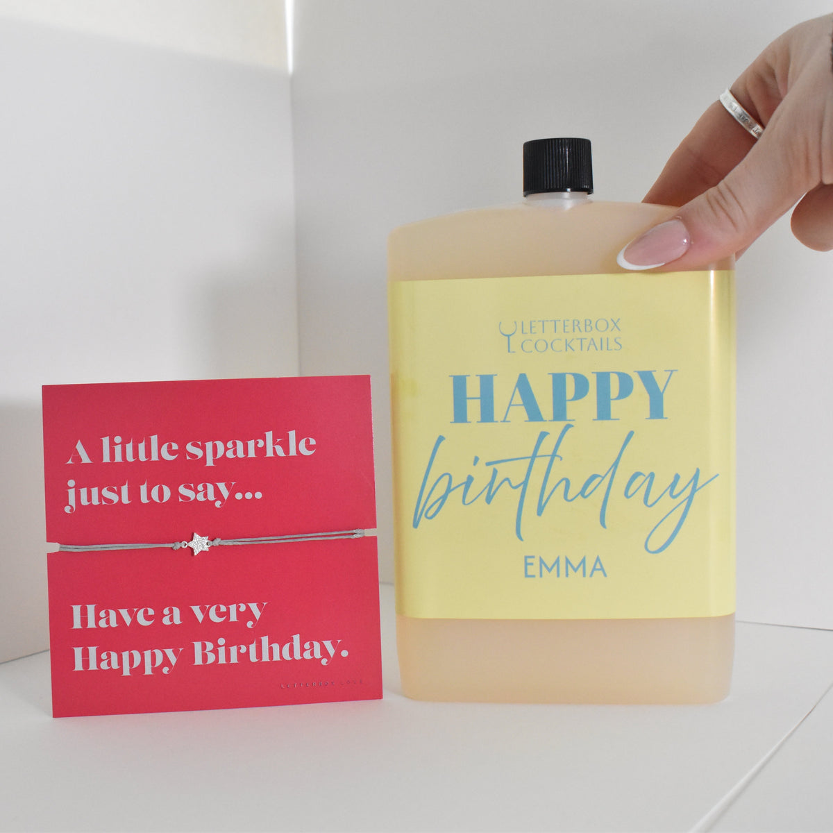 Bottle of letterbox cocktails with a happy birthday bracelet and personalised happy birthday cocktail on a white background