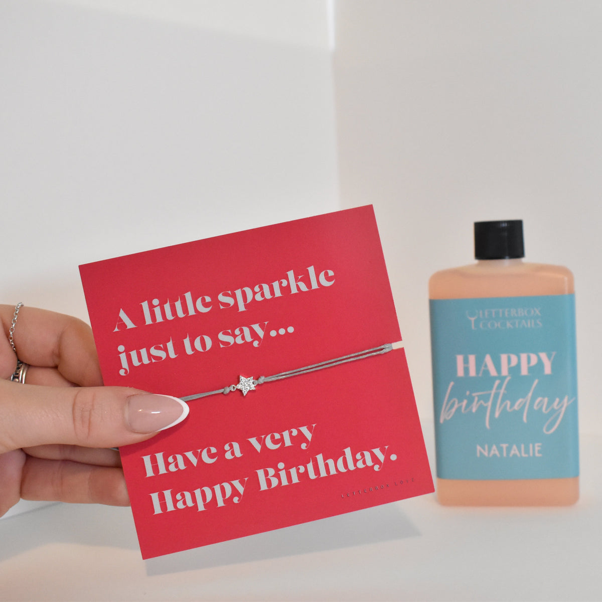 Bottle of letterbox cocktails with a happy birthday bracelet and personalised happy birthday cocktail on a white background